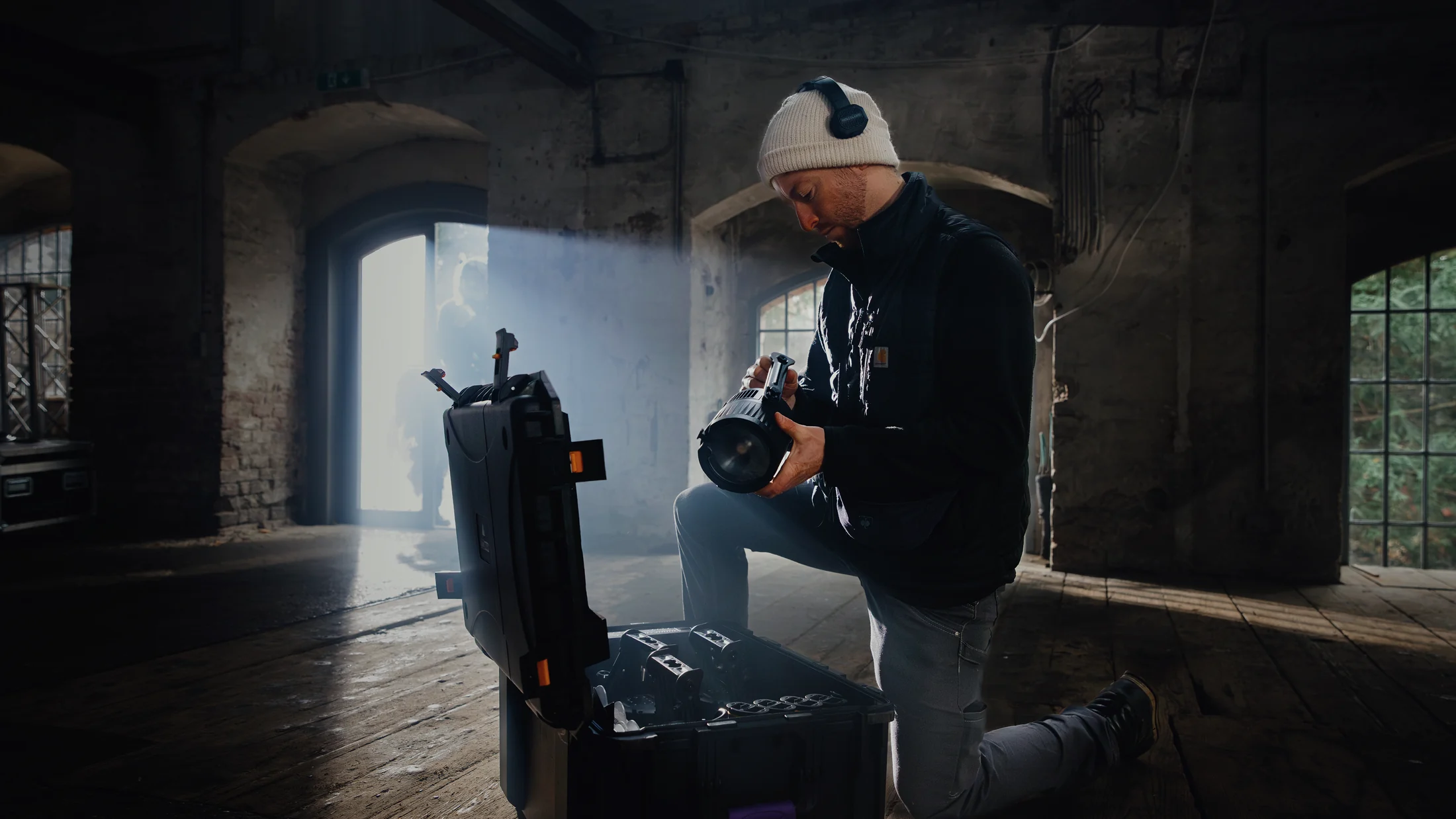 Technician setting up an Astera QuikBeam fixture beside a flight case in a doorway of light